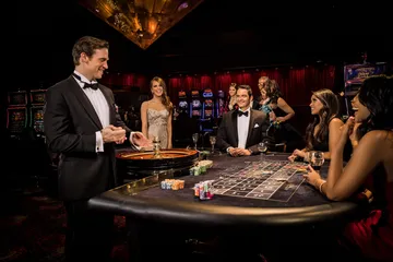 A professional dealer in a tuxedo greeting players at the roulette table, symbolizing the authentic live casino feel at JLWAFA.